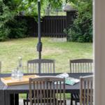 Außenbereich mit Tisch und Stühlen, Grasfläche und Gartenzaun im Hintergrund.