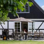 Terrasse mit Tisch, Stühlen und Sonnenschirm vor einem Fachwerkhaus.