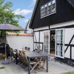 Terrasse mit Tisch, Stühlen und Sonnenschutz vor einem Fachwerkhaus.