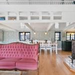 Ein Wohn- und Essbereich mit rosa Sofa, Holzboden und Hochbett.