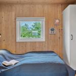 Schlafzimmer mit Holzwand, Bett, Fenster und Kleiderschrank.