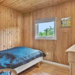 Schlafzimmer mit Holzwand, Bett, Fenster und Schrank.