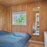 Schlafzimmer mit Holzwänden, Bett und Fenster zum Grün.