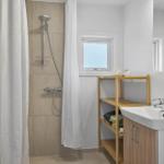 Badezimmer mit Dusche, Waschbecken und Holzregal.