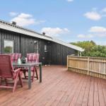 Terrasse mit Tisch und Stühlen vor einem Haus mit Holzwand.
