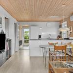 Wohnküche mit Esstisch, TV und Holzdecke.