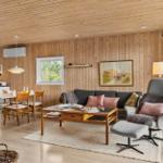 Wohn- und Essbereich mit Holzwand, Sofa, Sessel und Esstisch.