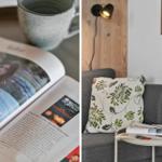 Ein grauer Sessel mit Kissen und einem Beistelltisch mit Tasse und Zeitung.