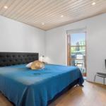 Schlafzimmer mit Bett, Stuhl und Fenster zur Terrasse.