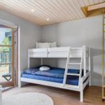 Zimmer mit Doppelstockbett, Holzdecke und Tür zum Balkon.