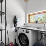 Wäscheschrank mit Waschmaschine, Spüle und Fenster mit Blick auf Grün.