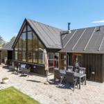 Moderne Villa mit großem Garten und Terrasse mit Sitzgelegenheiten.