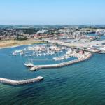 Hafen mit Booten und Steg, umgeben von Stadt und Industrie.