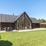 Moderne Villa mit großem Glasbereich und gepflegtem Garten. Außentisch mit Sitzgelegenheit.