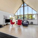 Wohnzimmer mit Kamin, roten Sesseln und großem Fenster