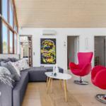 Wohnzimmer mit grauem Sofa, zwei roten Stühlen und großem Fenster.