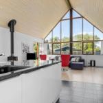 Küche mit Blick auf Wohnbereich mit rotem Sessel und großem Fenster