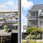 Terrasse mit Tisch und Stühlen. Blick auf Hafen mit Booten. Modernes Haus mit Balkon.