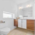 Badezimmer mit Waschbecken, Spiegel, Toilette und Dusche.