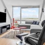 Wohnzimmer mit Sofa, Fernseher und Aussicht auf Hafen.