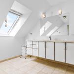 Badezimmer mit Dachschrägen, Fenster, Spiegel und Waschtisch.