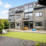 Moderne Villa mit Balkon, Terrasse und grünem Gartenbereich.