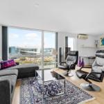 Wohnzimmer mit Sofa, zwei Sessel und Blick auf den Hafen.
