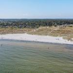 Strand mit Dünen und Ferienhäusern im Hintergrund