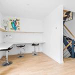 Helle Arbeitsfläche mit drei Barhockern und Treppe zur oberen Etage.