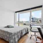 Schlafzimmer mit Bett, Schreibtisch und großem Fensterblick.