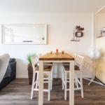 Essbereich mit Tisch, Stühlen und Küchenbereich mit Kühlschrank.