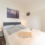 Schlafzimmer mit Bett, Nachttischen und Wandbildern.