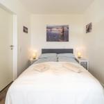 Schlafzimmer mit Doppelbett, Nachttischen und Wandbildern.