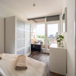 Schlafzimmer mit Bett, Kleiderschrank und Balkonzugang.