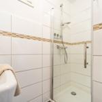 Badezimmer mit Dusche und Badewanne. Weiße Fliesen mit braunen Akzenten.