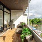 Terrasse mit Sitzgelegenheit und Blick auf einen Bootssteg.