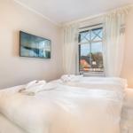 Zwei Betten mit weißen Bettwäsche, Fernseher und Fenster mit Blick.