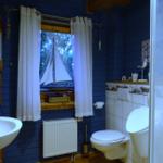 Badezimmer mit blauen Wänden, Fenster mit Segelbootmodell und Toilette.
