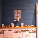 Badezimmer mit Holzregal, Seemöbeln und Muscheln an blauer Wand.