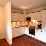 Küche mit weißen Schränken, Edelstahlspüle und Backofen.