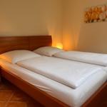 Doppelbett mit weißen Bettwäsche, Nachttisch und Wandbild mit Tulpen.