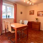 Esszimmer mit Tisch, Stühlen, Fenster und Schrank. Teppichboden und Wandbilder.