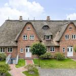 Rotes Backsteingebäude mit Strohdach und weißen Fenstern.