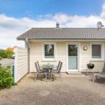 Haus mit Terrasse, Grill und Sitzgelegenheiten im Freien.