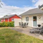 Terrasse mit Tisch, Stühlen und Liegen neben einem hellen Haus.
