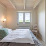 Schlafzimmer mit Bett, Fenster und Holzdecke.