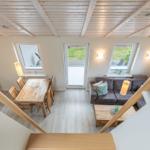 Wohn- und Essbereich mit Holzdecke, Sofa, Tisch und Fenstern.