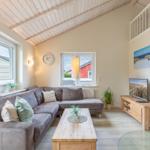 Wohnzimmer mit Sofa, Kamin und TV. Holzdecke und Fenster mit Blick.