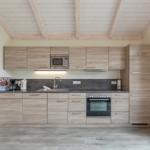 Küche mit Holzdecke, Edelstahlgeräten und Holzschränken.