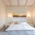 Schlafzimmer mit Bett, Nachttischen und Wandbild.